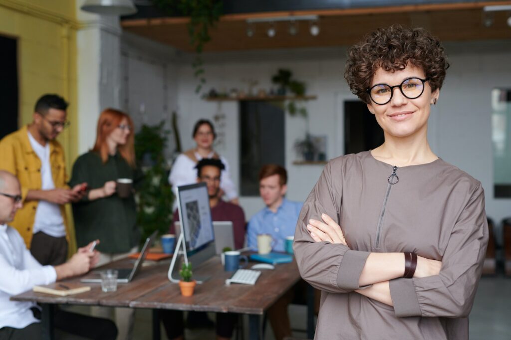 smiling woman with arms cross in front of a business meeting in an office